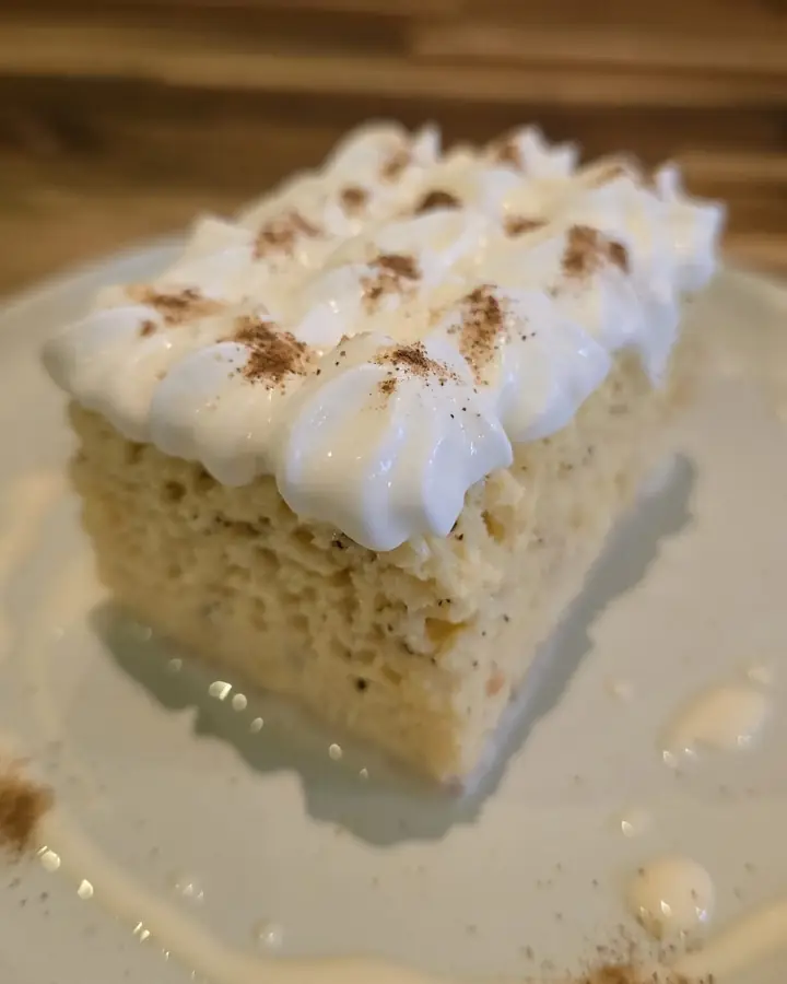 Slice of tres leches cake with whipped cream and cinnamon